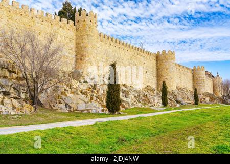 Mittelalterliche Steinmauer neben der alten Straße und blauem sonnigen Frühlingshimmel, Avila Spanien. Stockfoto