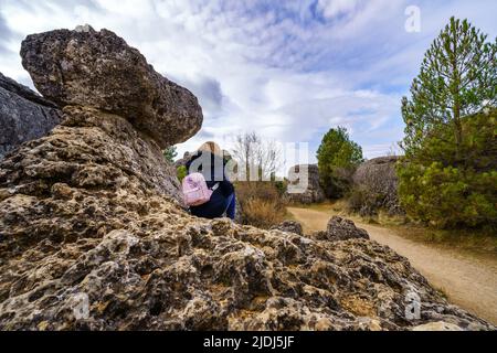 Frau, die auf einem großen Kalksteinfelsen in der verzauberten Stadt Cuenca sitzt. Stockfoto