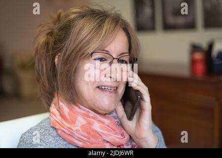 Weiße Frau mit lächelndem und glücklichen Gesicht, die in entspannter Haltung am Telefon spricht. Stockfoto