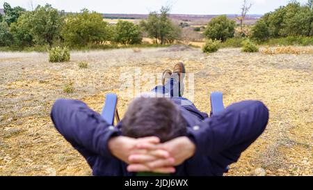 Mann, der auf einem Campingstuhl lag und sich entspannt auf dem Feld ausruhte. Stockfoto