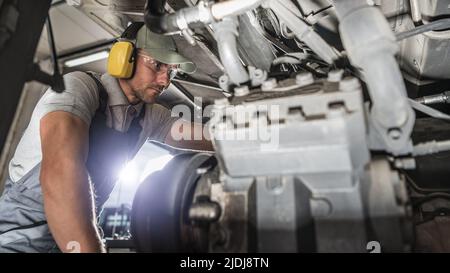 Kaukasischer Industriemechaniker in seiner 40s durchführenden Dieselanpusher-Wartung. Wartung Des Motorfahrers. Stockfoto