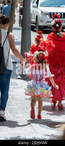 HUELVA, SPANIEN, 2. Juni 2022. Abfahrt der Bruderschaft von Rocío de Huelva durch die Straßen ihrer Stadt. Ein Mädchen, das als Flamenco gekleidet ist, geht zu t Stockfoto