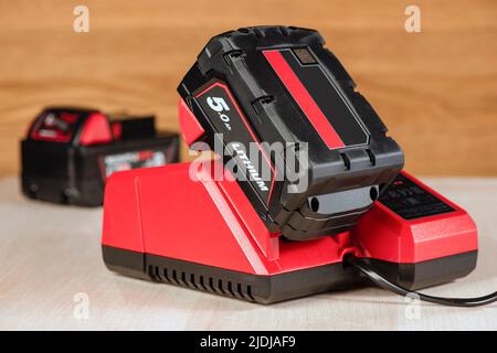 Der Vorgang, bei dem eine Lithiumbatterie von einem kabellosen Bauwerkzeug geladen wird. Der Akku des Schraubendrehers wird im Ladegerät geladen Stockfoto