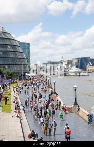 The Queen's Walk am Südufer der Themse in der Nähe der Tower Bridge in London, voll mit ausländischen Touristen und Touristen, die den Tag genießen. Stockfoto