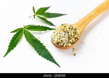 Grüne Cannabisblätter und Löffel mit abgeschälten Samen isoliert auf weißem Hintergrund. Ernährungsrechtliche Verwendung von Marihuana. Omega-3-Fette. Superfood Stockfoto