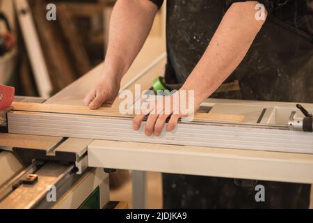 Nahaufnahme beschnittene männliche Tischlerhände, die mit Holzholz arbeiten, messen und sich auf den Schnitt vorbereiten. Holzarbeiten, Möbel machen Stockfoto