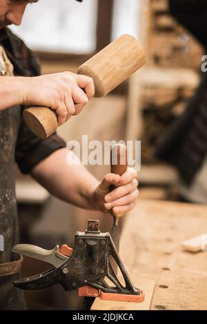 Vertikal von beschnittenen Mann Hände, Meister Schreiner mit Holzhammer und Meißel in der Werkstatt, Loft Möbel Interieur Stockfoto