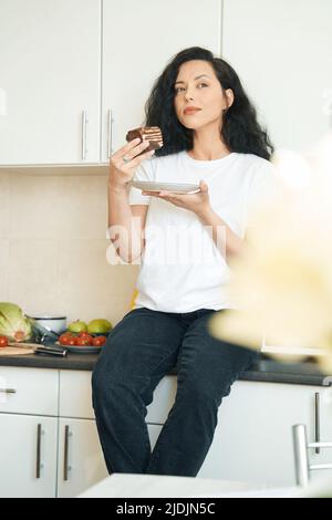 Nachdenkliche junge Frau mit Dessert und Teller Stockfoto