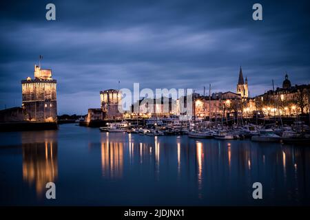 Panoramablick auf den alten Hafen von La Rochelle bei der blauen Stunde mit seinen berühmten alten Türmen Stockfoto