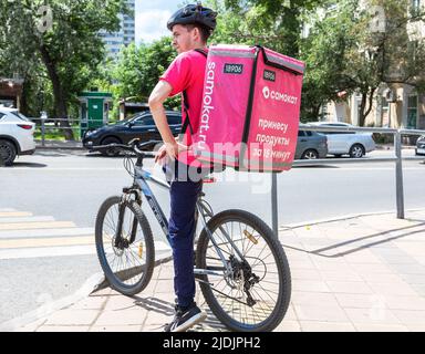 Samara, Russland - 18. Juni 2022: Kurier des Samokat-Lebensmittellieferdienstes auf dem Fahrrad auf der Straße der Stadt Stockfoto