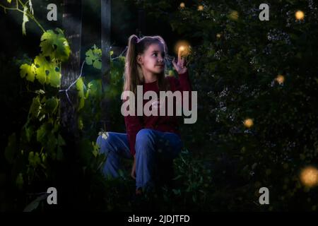 Kind im Abendgarten mit Glühwürmchen Stockfoto