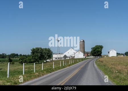 Amish Farm mit weißer Scheune und Windmühle. Stockfoto