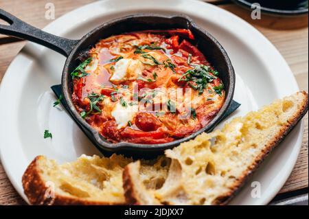 Shakshuka in eiserner Pfanne mit Brot serviert Stockfoto