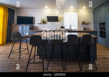Interieur der modernen Küche mit Holzboden und großem Tisch in der Mitte des Raumes. Stockfoto