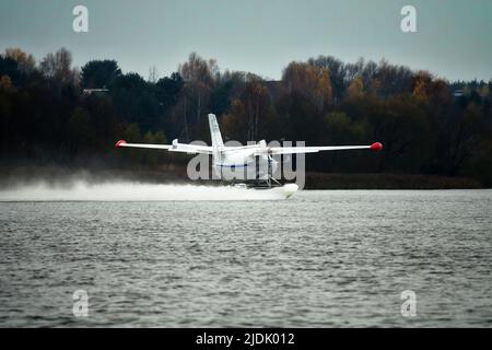 Das zweimotorige Wasserflugzeug ein Wasserflugzeug steigt aus dem Wasser, aus dem Waldsee, dem nördlichen Land auf. Wasserflugzeug Stockfoto