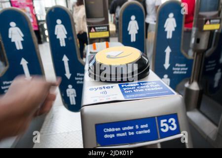 Filmbild eines Mannes, der versucht, das Ticket vom Ticketautomaten an der Ticketbarriere des Nationalbahnhofs zu nehmen Stockfoto