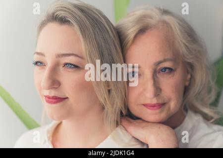 Nahaufnahme von zwei blonden, wunderschönen Frauen aus den Jahrtausenden mit blauen Augen, die Make-up tragen, eine Frau, die sich auf die Schultern lehnt. Hochwertige Fotos Stockfoto