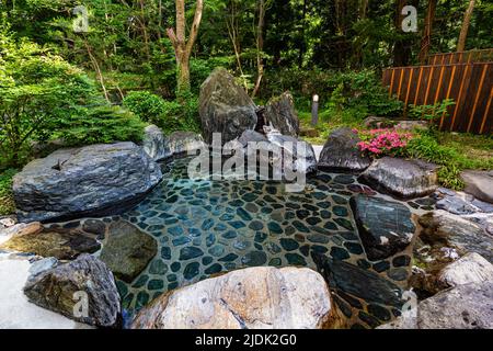 Rotemburo ist eine heiße Open-Air-Quelle, die in Japan als „Rotemburo“ bezeichnet wird. Baden in einer natürlichen Atmosphäre, unter den Bäumen und unter freiem Himmel ist ein Favorit Stockfoto