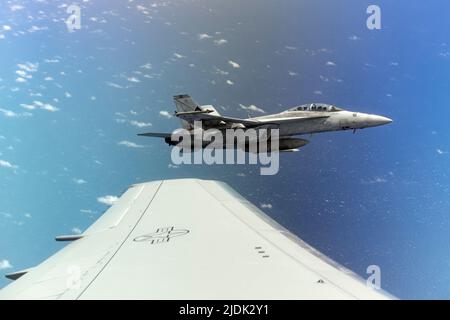 Ein US Navy F/A-18 Hornet Banks links in Formation neben einem McConnell Air Force Base, Kansas, KC-46A Pegasus 6. Juni 2022, während der Air Mobility Command's Employment Concept Übung 22-06. Der F/A-18 hat gerade Kraftstoff erhalten und wartet darauf, dass sein Flügelmann sein Tanken durch den Pegasus beendet. McConnell Aircrew und Tanker lieferten im Indo-Pacific Theatre Luftbetankung, um die gemeinsame Interoperabilität in einer Multi-Domain-Umgebung zu üben, um die Leistungsfähigkeit und Bereitschaft in der Praxis zu steigern. (USA Luftwaffe Foto von Master Sgt. John Gordinier) Stockfoto