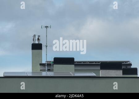 Dach des Gebäudes mit Schornsteinantennen und Sonnenkollektoren des Neubaus Stockfoto