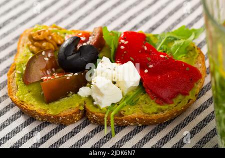 Sandwich mit Guacamole auf gestreiftem Textilhintergrund Stockfoto