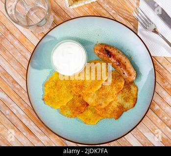 Kartoffelpfannkuchen mit Wurst und Sauerrahm Stockfoto