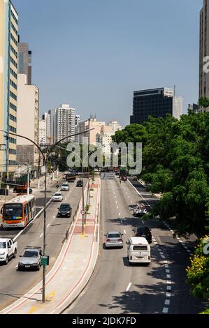 Südwestlicher Blick auf beide Wege der Antarktis Avenue mit einer Fahrradspur in der Mitte und normalem Geschäftsverkehr, der unter blauem Himmel vorbeifährt. Stockfoto