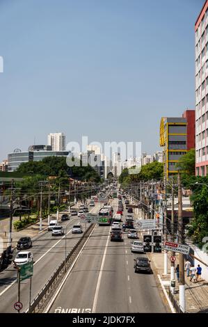 Starker Verkehr, der an beiden Wegen der Francisco Matarazzo Avenue im Agua Branca Viertel vorbeiführt, mit vielen Wolkenkratzern im Hintergrund unter sonnigem blauen Himmel. Stockfoto