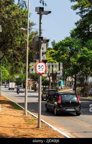 Ein Radarfalle mit einem 50-km-Geschwindigkeitsbegrenzungsschild direkt unterhalb der Straße, das die Geschwindigkeit des vorbeifahrenden Verkehrs an einem normalen Tag auf der Paulo VI Avenue überprüft. Stockfoto