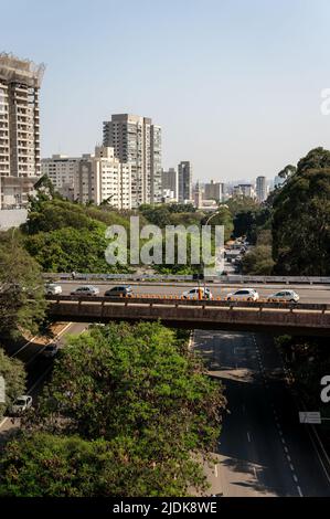 Das Doutor Joao Tranchesi Viadukt, umgeben von grüner Vegetation, die über die Avenida Paulo VI mit dem Pinheiros-Viertel hinter dem Hotel unter sonnigem, blauem Himmel führt. Stockfoto