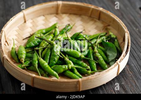 Grüner kleiner indonesischer Chili oder Cabe Ijo für Gorengan, serviert auf Bambusplatte Holztisch. Ausgewählter Fokus Stockfoto