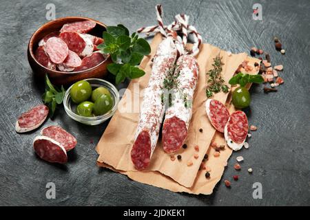 Traditionelles spanisches Fuet auf grauem Hintergrund. Trockene Schweinswürste mit eigenarnem Geschmack. Stockfoto