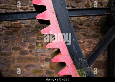 Rot lackiertes Riesenrad mit alter Steinmauer im Hintergrund Stockfoto
