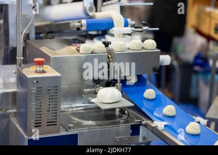 Automatische Lebensmittelmaschine in der Fabrik der Lebensmittelindustrie, baozi chinesische Brötchen Wrap Maker Maschine. Stockfoto