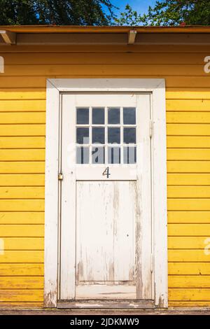 Weiße Holztür auf einer gelben Strandhütte Stockfoto