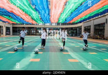 YANTAI, CHINA - 23. JUNI 2022 - Kinder spielen Fußball auf einem Spielplatz in einem experimentellen Kindergarten im Bezirk Penglai in Yantai, dem Shand in Ostchina Stockfoto