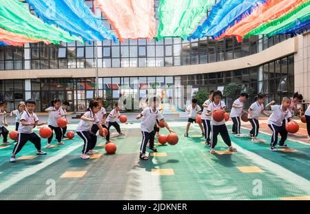 YANTAI, CHINA - 23. JUNI 2022 - Kinder haben ein Basketballspiel auf dem Spielplatz eines experimentellen Kindergartens im Bezirk Penglai in Yantai, Ost Stockfoto