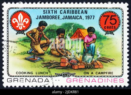 GRENADA UND GRENADINEN - UM 1977: Eine in Grenada gedruckte Marke zeigt Kochen, 6. Caribbean Jamboree, Kingston, Jamaica, um 1977 Stockfoto