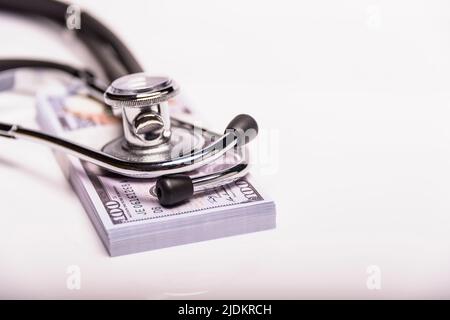 Medizinisches Konzept - Stethoskop über den Dollarscheinen isoliert auf weißem Hintergrund. Stockfoto