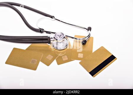 Gesundheitskosten konzeptionelles Bild: Stethoskop und Geldhaufen auf einer medizinischen Karte, Symbol der Gesundheitskosten oder Krankenversicherung, isoliert auf Stockfoto