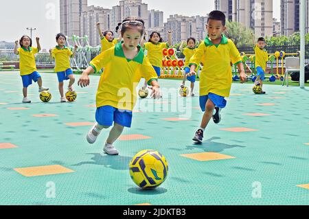 YANTAI, CHINA - 23. JUNI 2022 - Kinder spielen Fußball im Fumiao Kindergarten im Bezirk Fushan in Yantai, der ostchinesischen Provinz Shandong, 22. Juni 202 Stockfoto