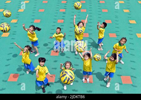 YANTAI, CHINA - 23. JUNI 2022 - Kinder spielen Fußball im Fumiao Kindergarten im Bezirk Fushan in Yantai, der ostchinesischen Provinz Shandong, 22. Juni 202 Stockfoto