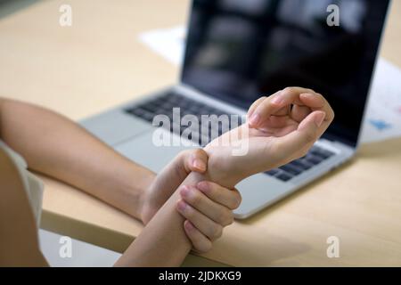 Eine junge Frau verletzte sich lange Zeit am Handgelenk, weil sie einen Laptop benutzte. Nahaufnahme Stockfoto