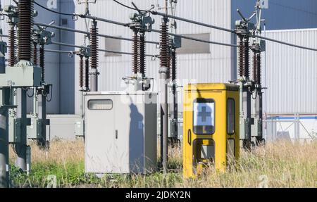 Hannover, Deutschland. 22.. Juni 2022. Zwischen den Transformatoren des Steinkohlekraftwerks steht eine alte Telefonzelle mit einem Notfallsymbol. Das Kraftwerk wird vom Energieversorger enercity und der Volkswagen AG betrieben und beliefert unter anderem das VW-Werk in Hannover. Das deutsche Wirtschaftsministerium will den Einsatz von Gas für die Stromerzeugung und die Industrie angesichts der gedrosselten russischen Versorgung reduzieren. Stattdessen sollen mehr Kohlekraftwerke eingesetzt werden. Quelle: Julian Stratenschulte/dpa/Alamy Live News Stockfoto