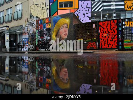 STREET-ART-PORTRÄT EINER UKRAINISCHEN FRAU, DIE EINEN HUT IN IHREN LÄNDERFARBEN TRÄGT, ZEIGT DIE UNTERSTÜTZUNG FÜR DIE UKRAINE NACH DER RUSSISCHEN INVASION IM FEBRUAR 22. Stockfoto