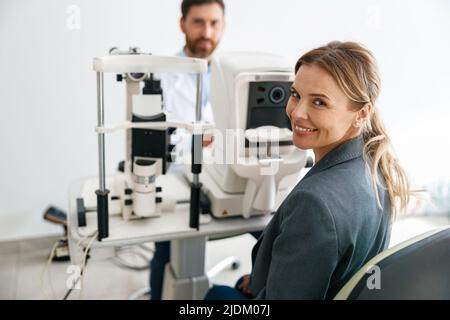 Lächelnde Patientin wartet auf einen Sehtest im Augenoptikgeschäft oder in der Augenklinik Stockfoto