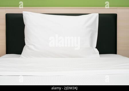Weißes, sauberes Kissen auf einem Bett in einem Hotelzimmer, Vorderansicht Stockfoto