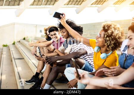 Multirassische Gruppe von Teenagern, die im Freien ein Mobiltelefon benutzen Stockfoto