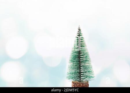 Grüner Weihnachtsbaum auf einem blauen abstrakten Winterhintergrund mit schimmernden weißen Sonnenflecken. Bokeh. Neujahrs- und Weihnachtskonzept. Platz für Text kopieren. Stockfoto