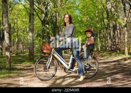 Mutter mit Kind auf Elektrofahrrad im Park Stockfoto